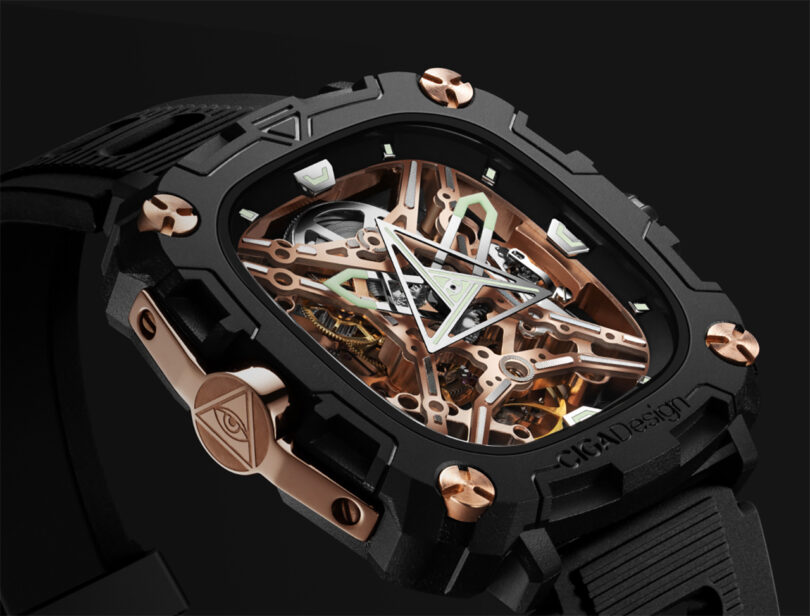 Black and gold CIGA Design Eye of Horus mechanical wristwatch from front overhead view with soft white glow behind it.