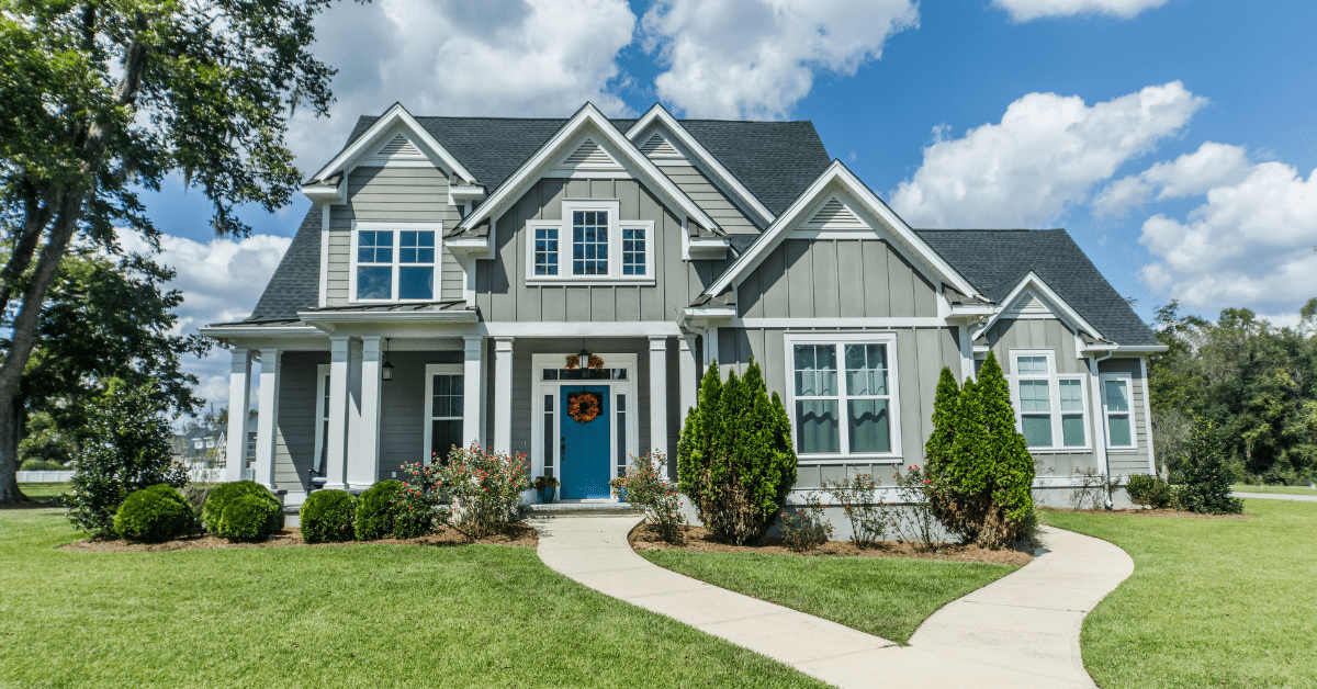 A large Craftsman styled house with green landscaping and curvy walkway.