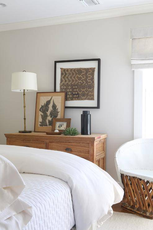 A gold bamboo lamp complements a farmhouse dresser styled with layered art and placed under a framed fabric art piece.