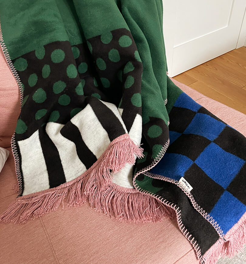 pink, blue, green, white, and black geometric abstract throw blanket on a pink sofa
