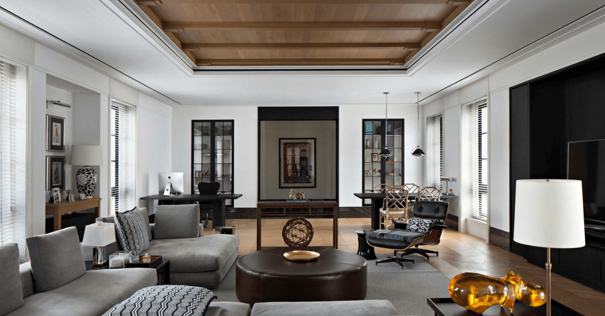 Modern living room with grey furniture and wood ceiling beams.