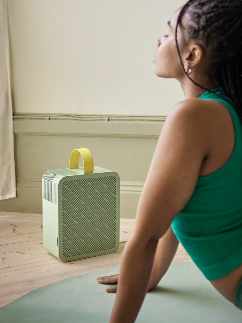 partial view of woman holding herself up from the floor with her arms straight with square green box beside her