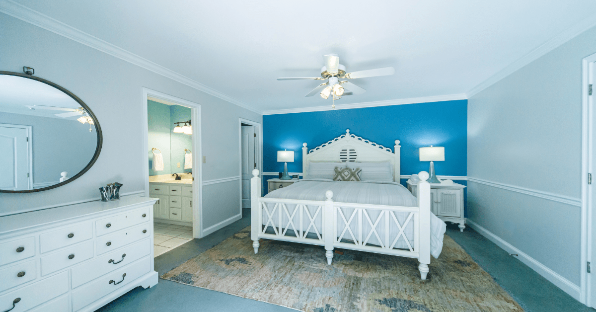 Bedroom with bed, rug, and white furniture. 