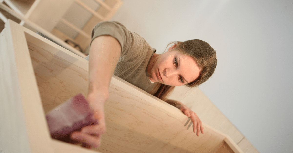 Person sanding down kitchen cabinets.