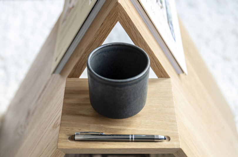 detail of triangle-shaped wooden side table holding a book and mug