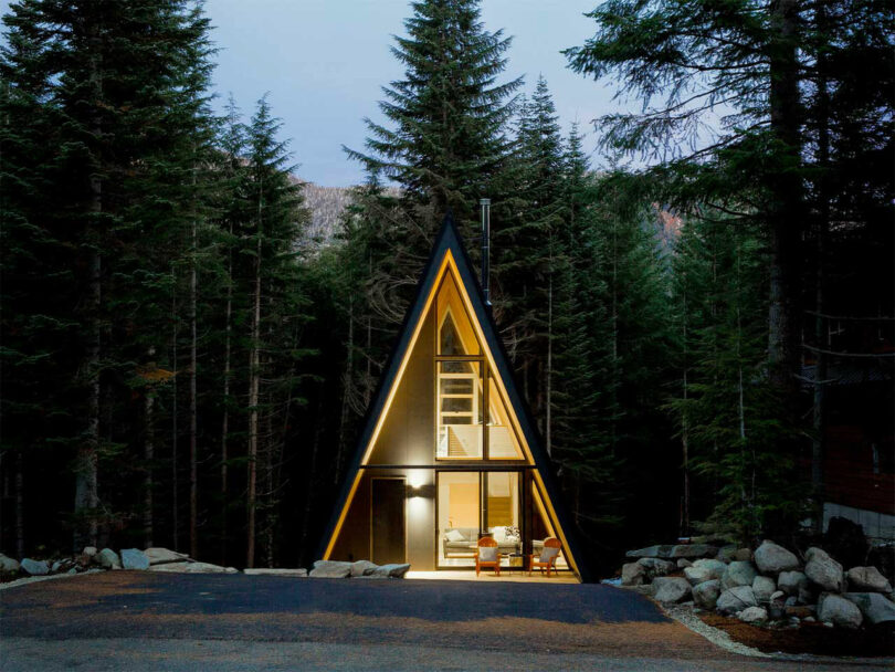 angled evening view of modern a-frame house with lights on inside