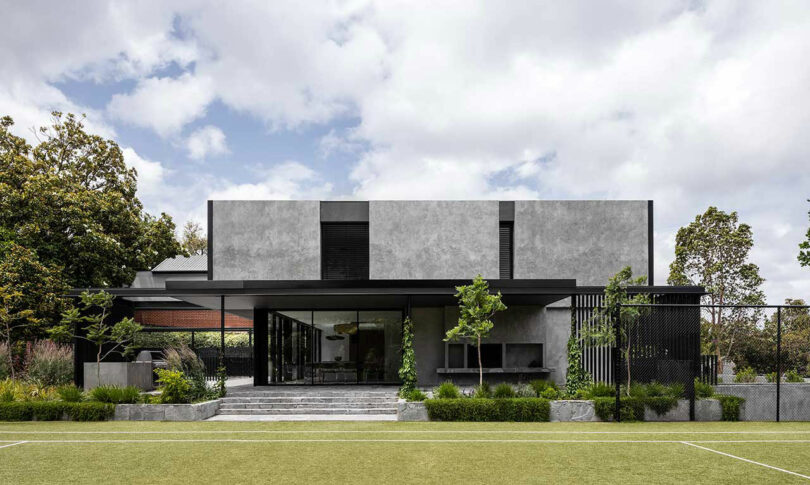 exterior view of large modern black house with green yard