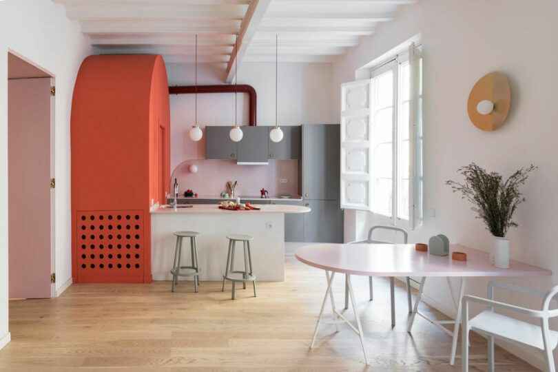 interior view of open modern apartment with a pink and coral colored kitchen