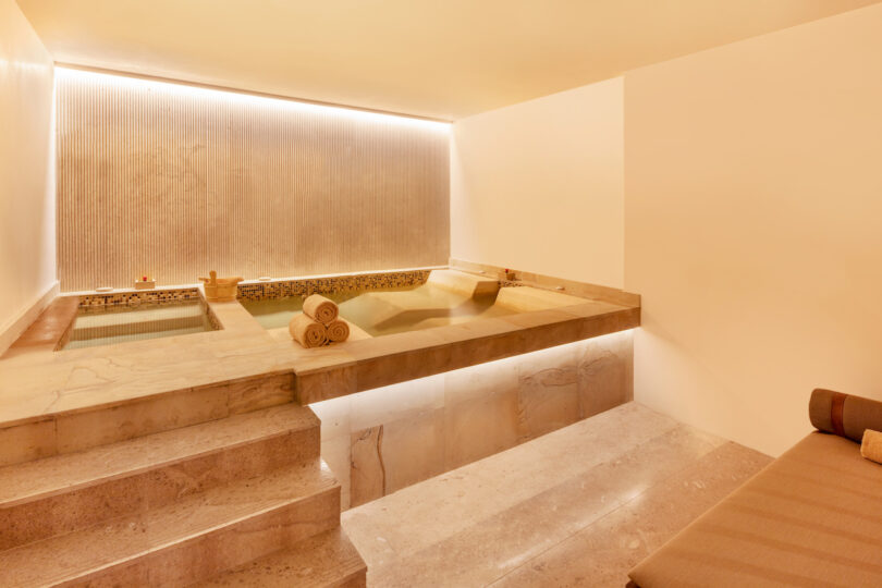 Nobu Los Cabos spa bathing room with elevated lounging soak pools bathed in warm lights.