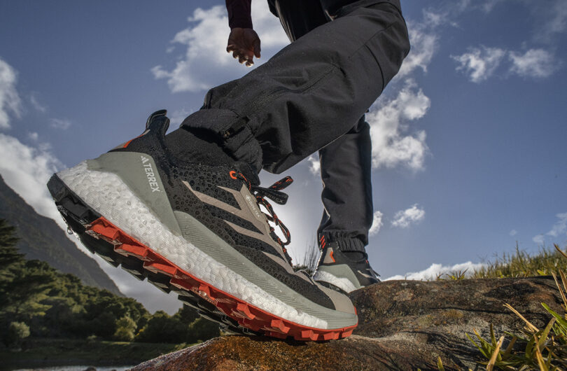 Exaggerated fish eye angled perspective from ground level of someone hiking by wearing TERREX Free Hiker 2 Low GTX hiking shoes, with blue skies and small wisps of clouds overhead.