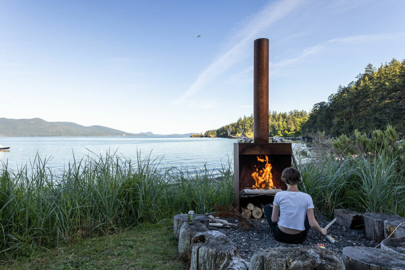person sitting in front of wood burning stove on waterfront