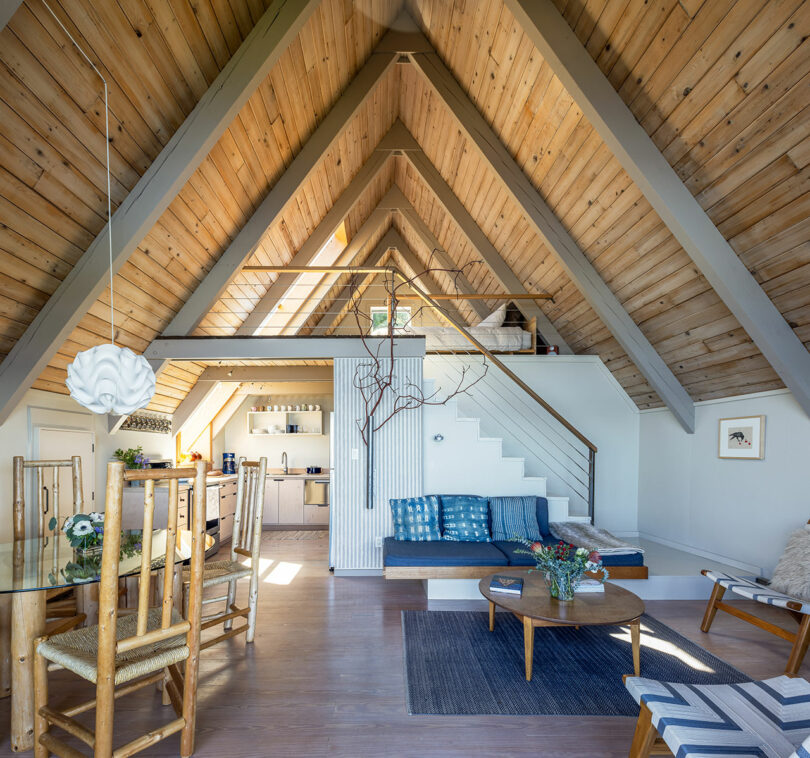 Interior view of modern a-frame cabin with pitched light wood ceiling and open modern living space