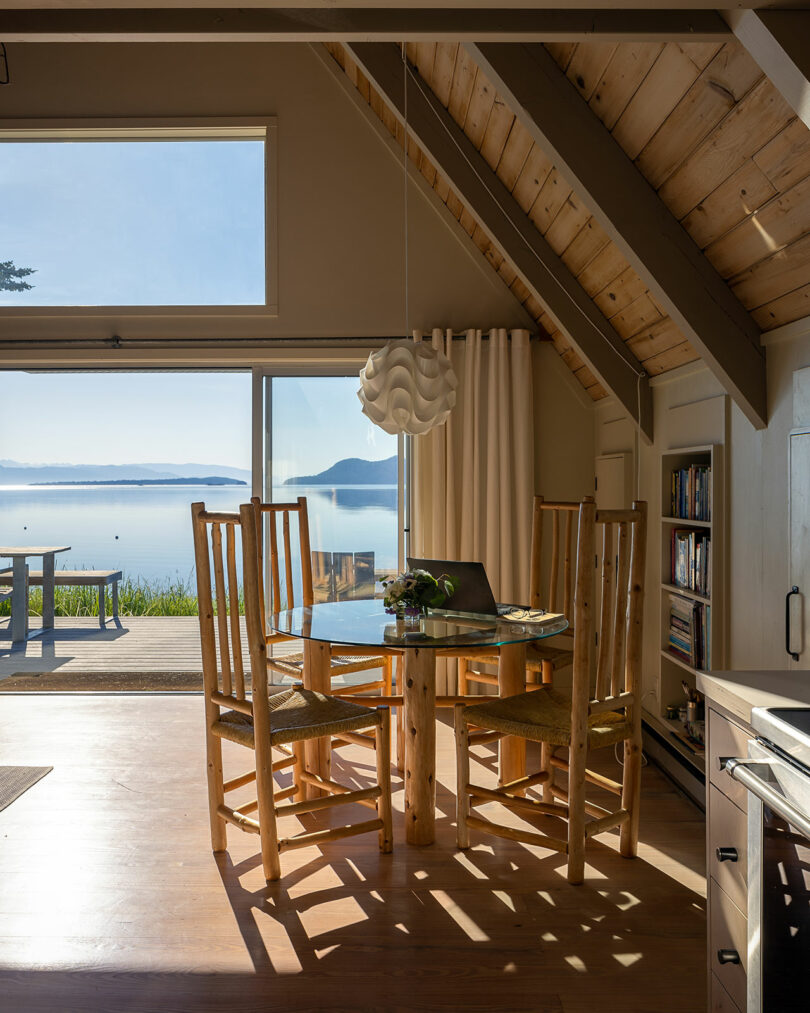 partial interior view of modern cabin with wood dining set and views of water behin