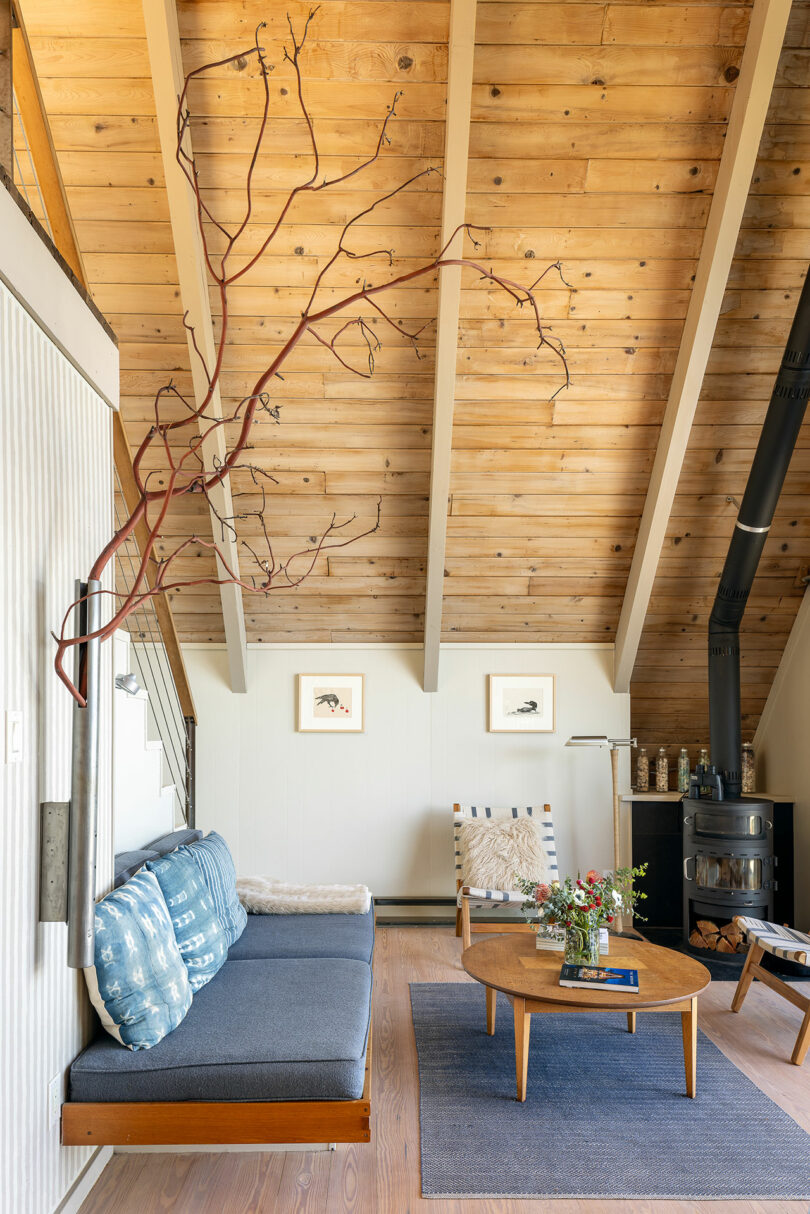 partial living room view of modern cabin with slanted wood ceiling and blue daybed