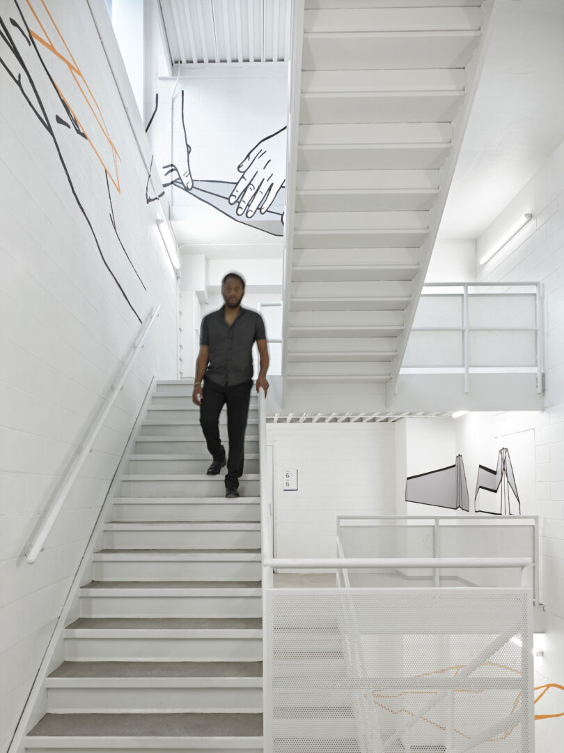 perspective art in white stairwell, man walking down the stairs