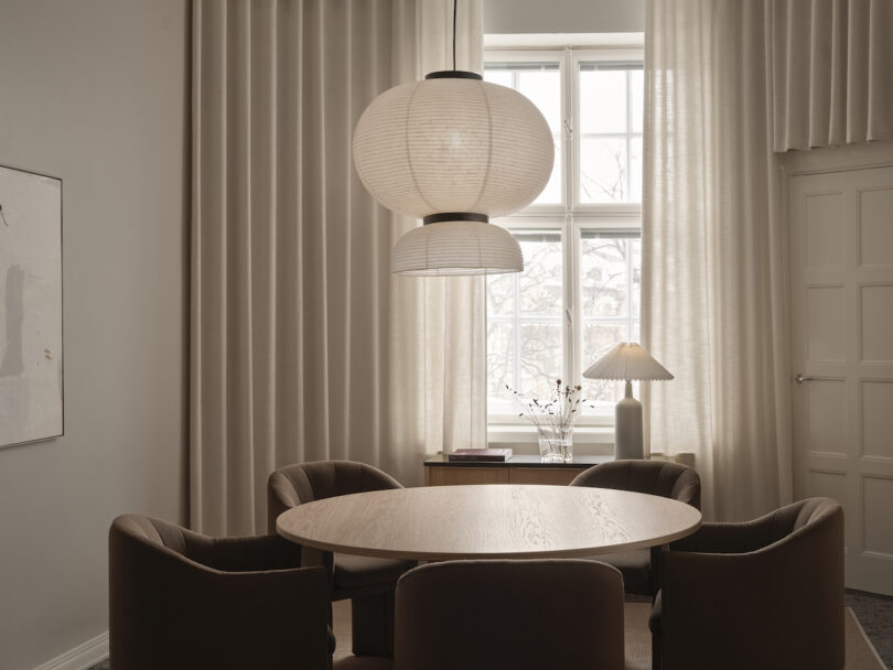 round table surrounded by brown chairs under a paper pendant