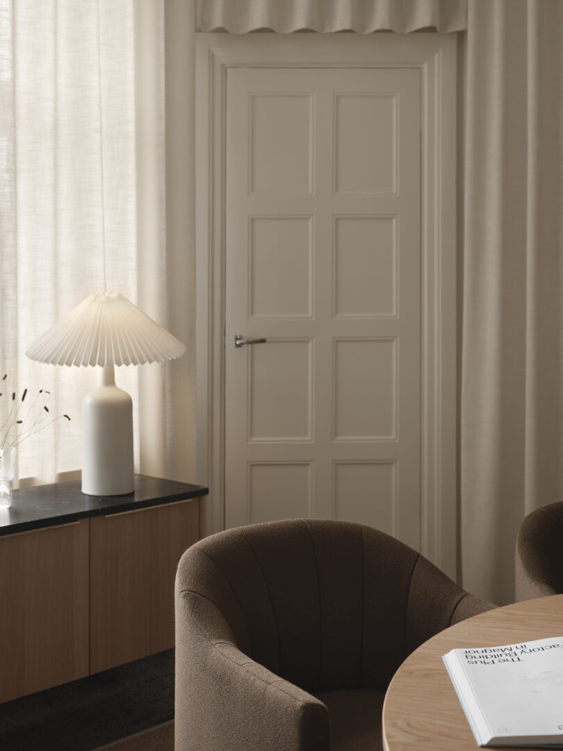 white table lamp and console next to round table and brown chairs