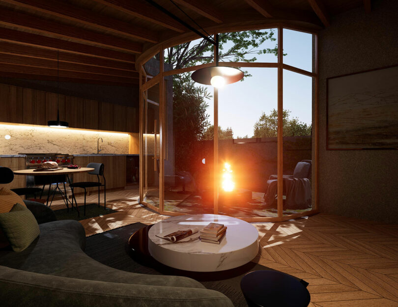 interior evening view of small modern house with sofa looking out curved wall of windows to fire pit outside