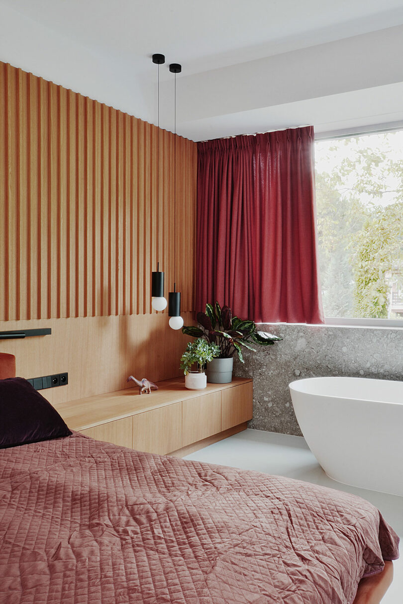 partial angled view of modern bedroom with wood wall and built-in storage table and floating bathtub