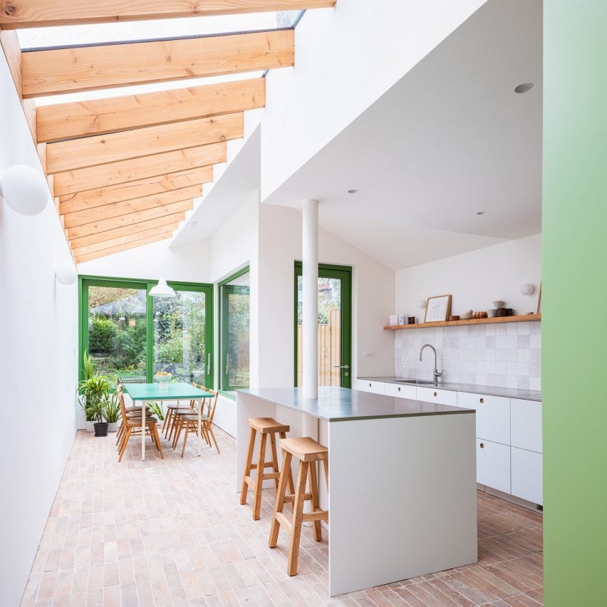 Open-plan kitchen with white walls and brick floor 