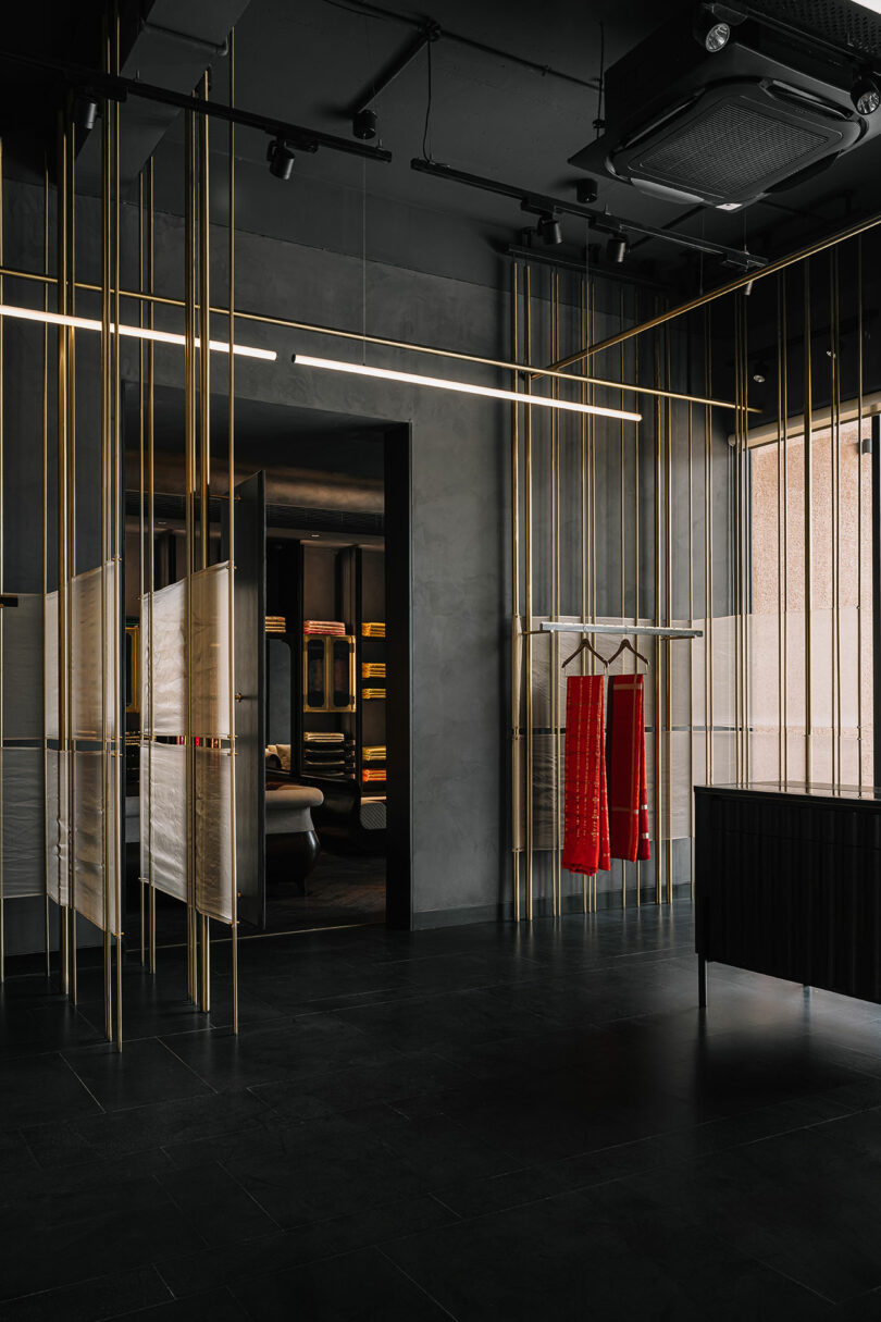 Vertical gold rods from which shelves are built and garments hang. Shelving in the wall.