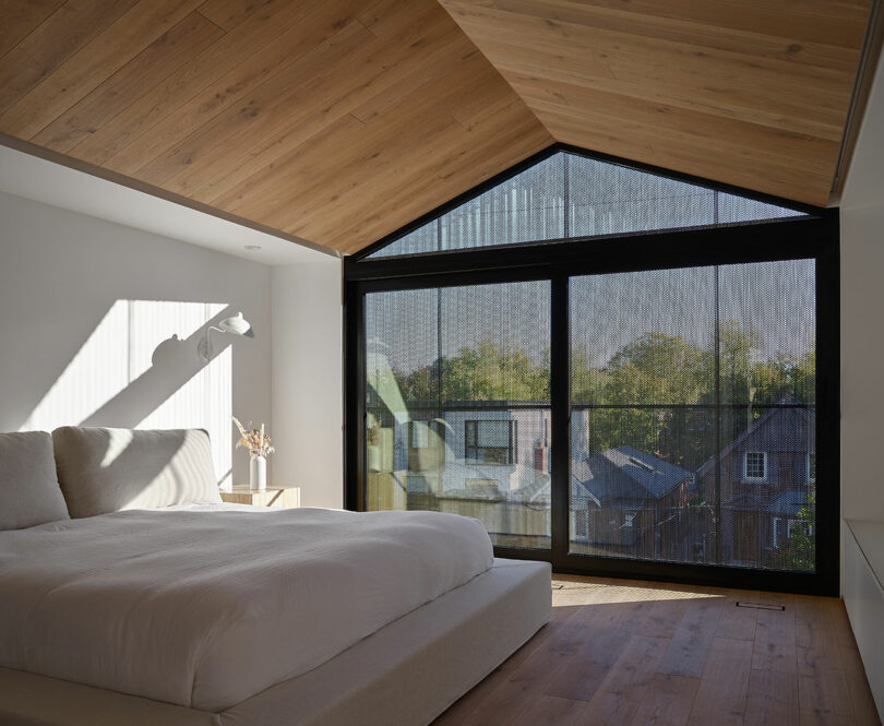 angled partial view of modern minimalist bedroom with white bedding