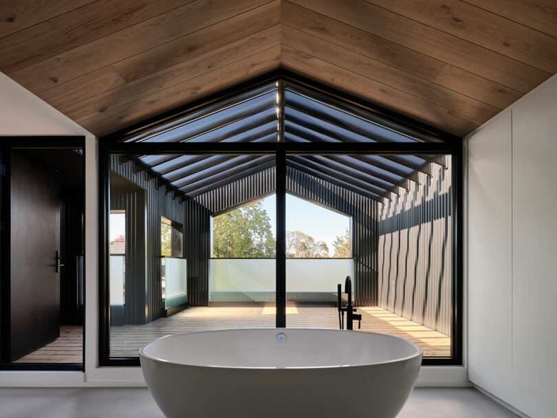 view inside modern bathroom with floating tub in front of large gabled exterior room