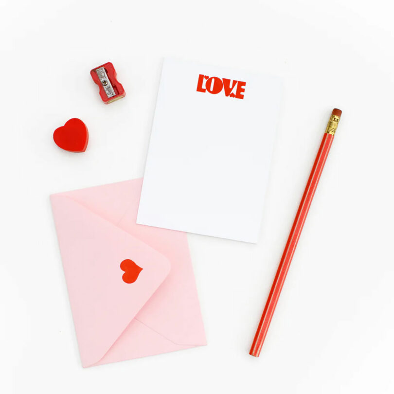 A Valentine's Day Stationary Set with white note card, pink envelope, and red pencil, eraser, and sharpener.