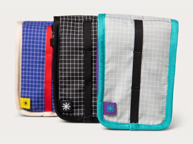 Three Point and Shoot Camera Pouches lined up, one in creme multicolored version, another in cosmic purple, and an all black version.