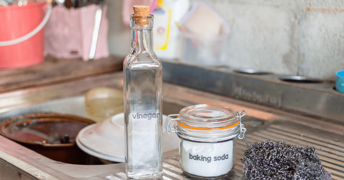 A bottle of vinegar flanked by a stainless steel sink.