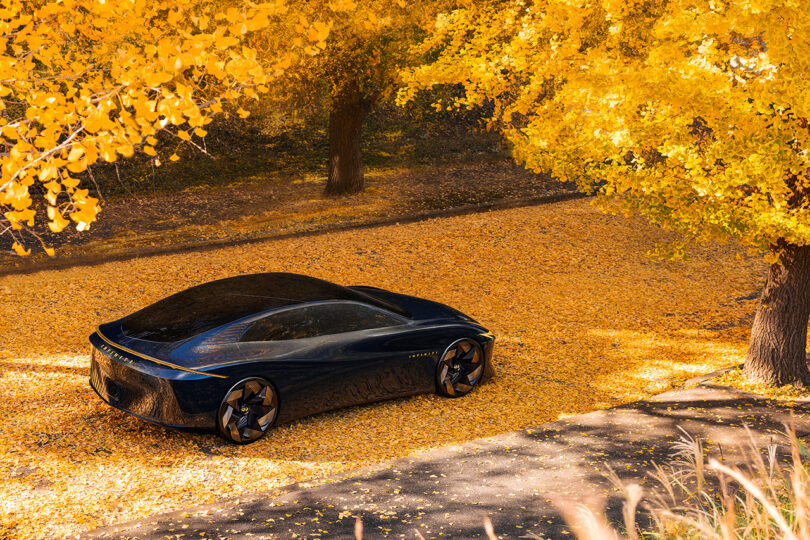 All-electric Vision Qe fastback sedan parked in a golden autumn hued setting of trees.