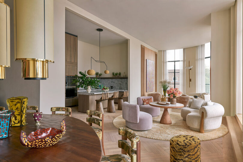 open modern living space with pastel upholstered chairs in living room and seating area with view into kitchen in distance