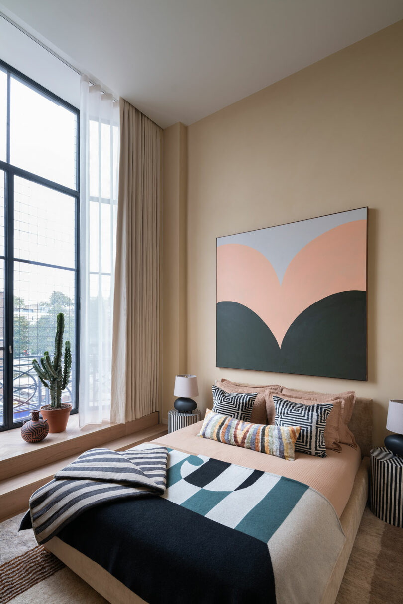 angled view of modern bedroom with graphic patterns on bedding and painting above bed