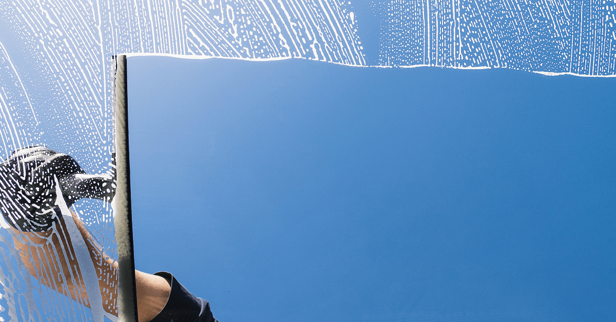 A window being cleaned with squeegee with a blue sky outside.