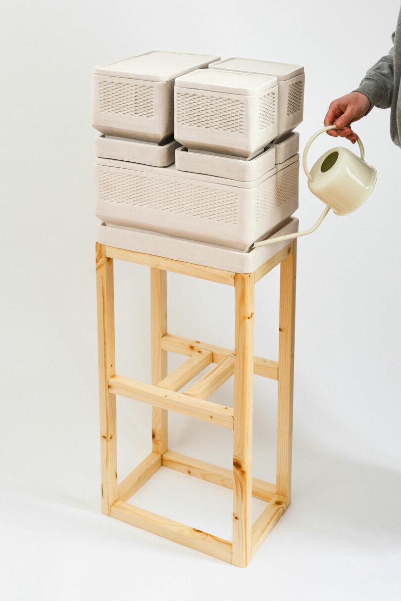 wood table holding clay boxy food storage containers stacked