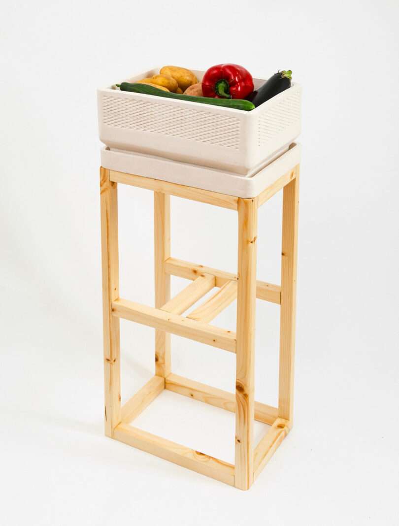 wood table holding clay boxy food storage containers stacked holding fruit