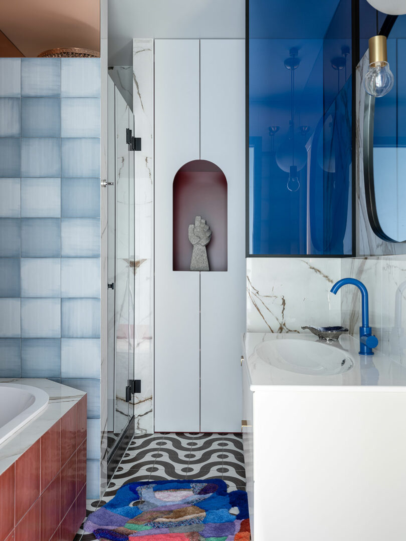 angled view of modern bathroom with swirly walls and single white sink and blue faucet and red bathtub