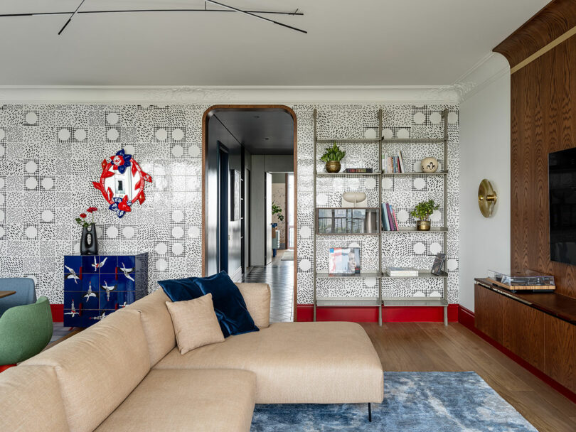 view of modern living room with tan sectional sofa with wall-mounted chrome bookshelf filled with random objects