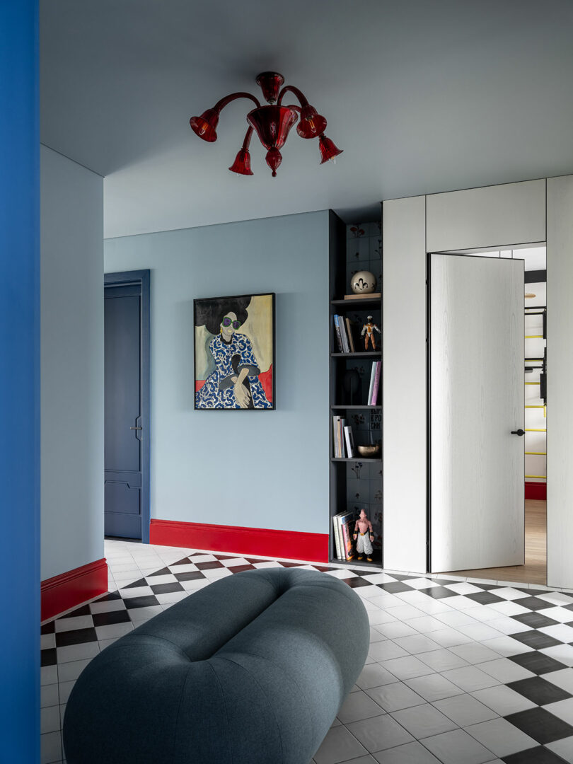 angled view of open hallway in modern apartment with light blue pouf in center on black and white tile floor