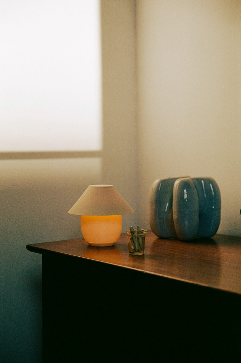 A tiny orb-shaped lamp with traditional shade sitting on a dresser.