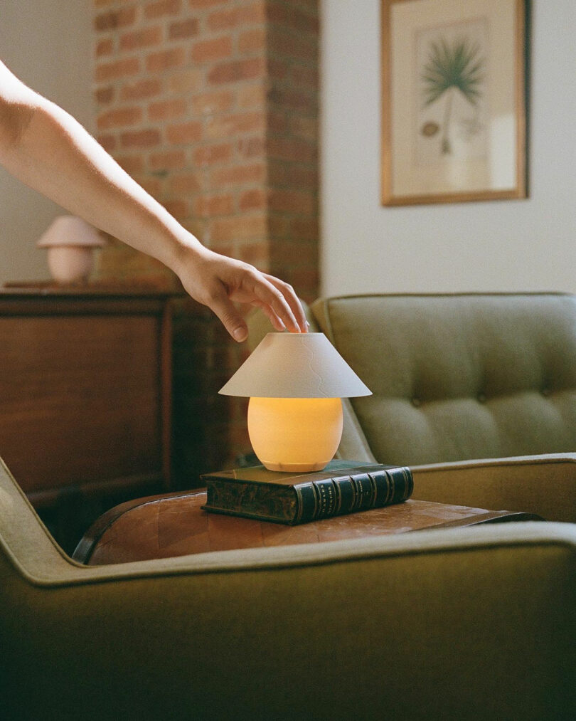 A tiny orb-shaped lamp with traditional shade being turned on.