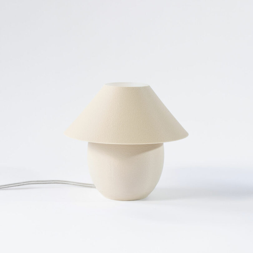 A tiny, eggshell colored orb-shaped lamp with traditional shade turned off.
