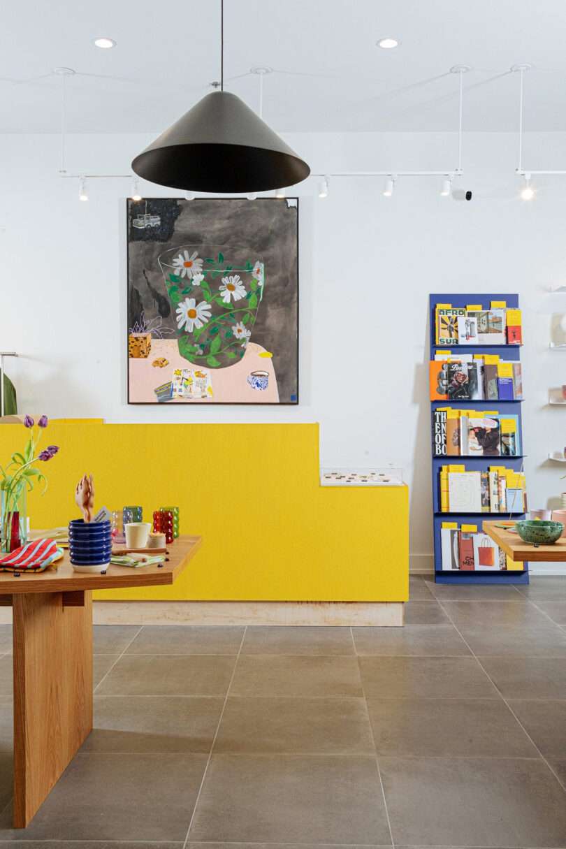 YOWIE hotel shop and lobby with yellow counter display and black cone pendant lamp overhead