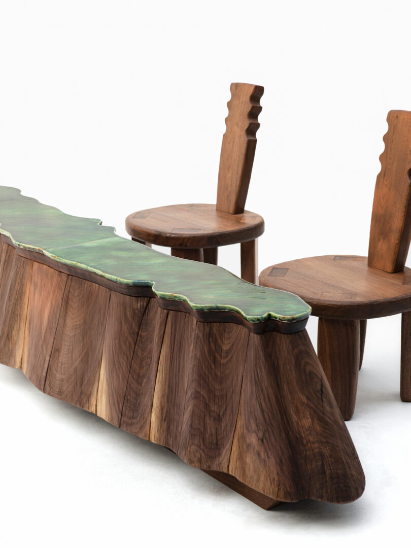 green sculptural table with two wood chairs