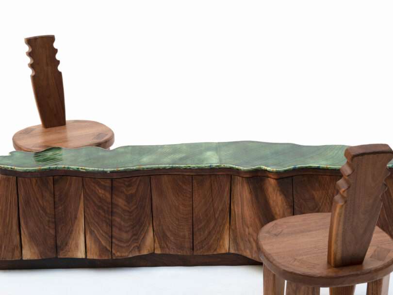green sculptural table with two wood chairs