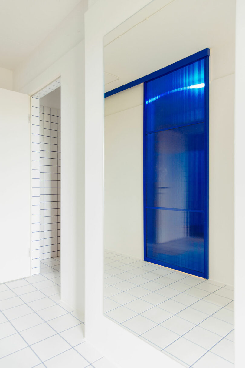 angled interior shot of white hallway with bright blue glass window