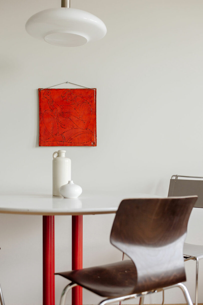 closeup view of modern dining set with red pedestal table and red art on wall