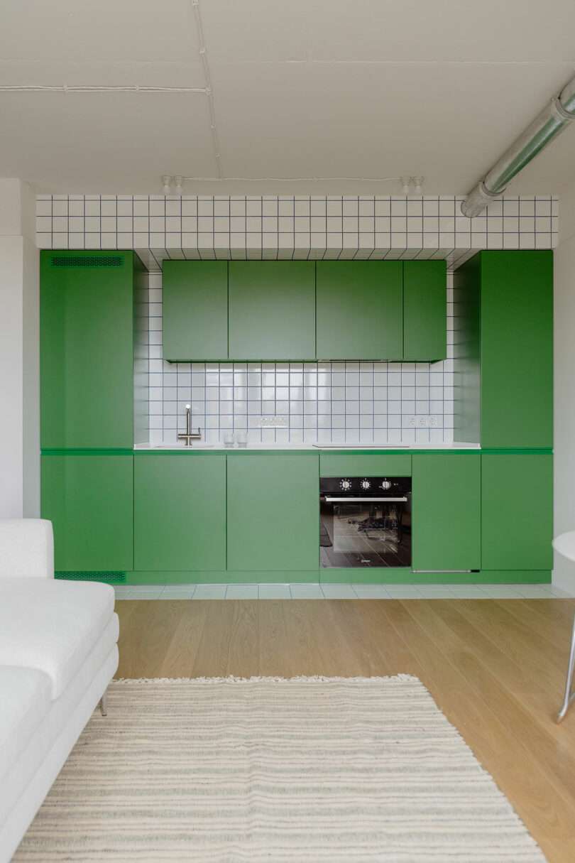 modern minimalist living space looking towards kelly green kitchen