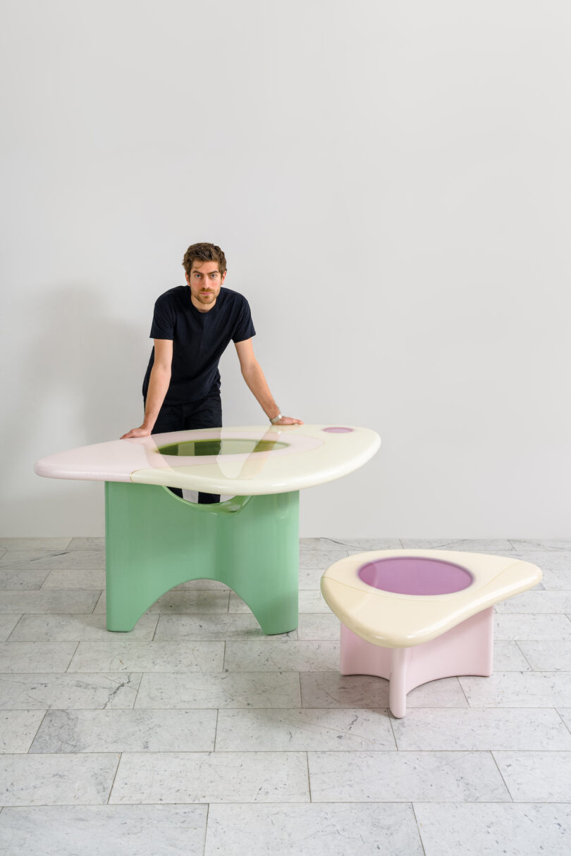 man standing next to two tables