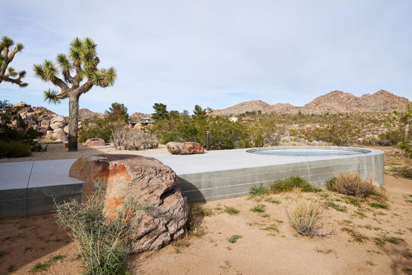 angled outside view of elevated concrete patio in desert with circular pool at end